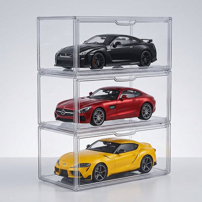 Three stacked clear acrylic toy car display boxes holding miniature sports cars: a black car on top, a red car in the middle, and a yellow car on the bottom, photographed on a light gray studio background.
