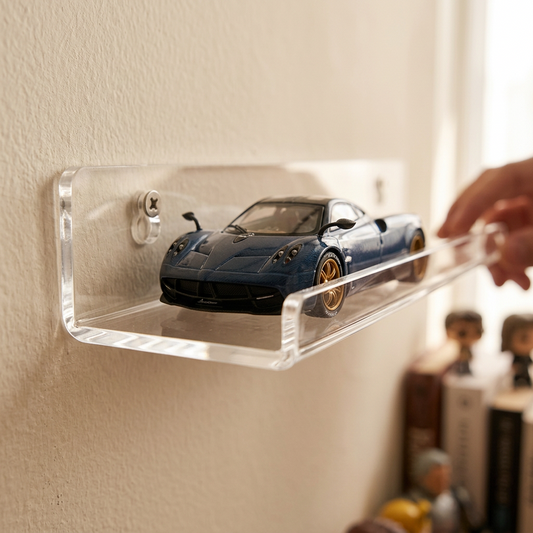 A clear acrylic display shelf mounted on a beige wall, holding a blue sports car model. A hand is adjusting the shelf, with blurred books and figurines in the background.